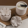 A white ceramic cup filled with cream-colored wax, next to a floral silicone mold and a wooden surface.