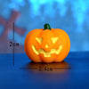 An orange carved pumpkin figurine with a smiling face and green stem, displayed on a blue surface.