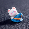 A white cartoon bear figurine wearing a blue pumpkin costume with orange accents.