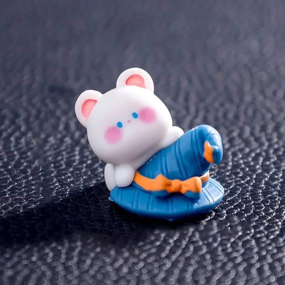 A white cartoon bear figurine wearing a blue pumpkin costume with orange accents.