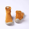 A pair of soft-soled baby first walker socks shoes in orange with a light gray sole.