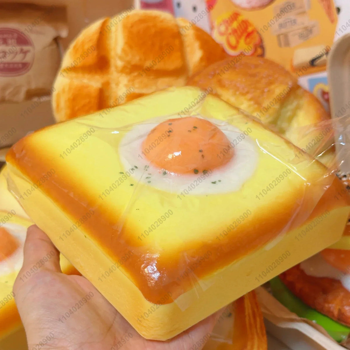 A hand holds a yellow squishy fried egg toast stress relief toy with a cooked orange yolk.