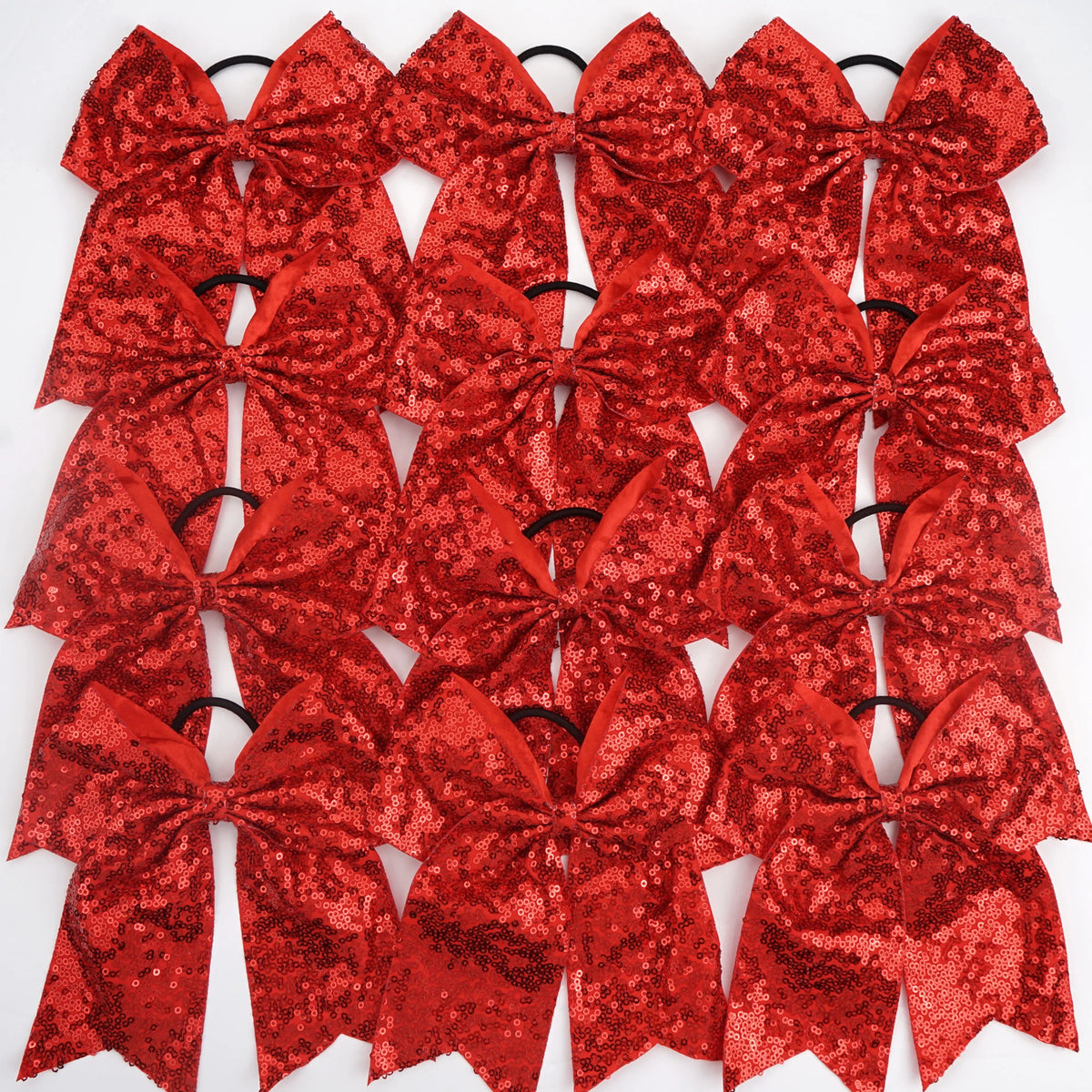 A pack of twelve red glitter sequin pigtail bows for girls with elastic hair ties.