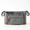 A gray fabric stroller organizer bag with multiple pockets and hanging hooks.