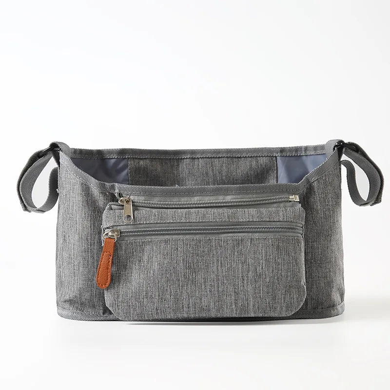 A gray fabric stroller organizer bag with multiple pockets and hanging hooks.