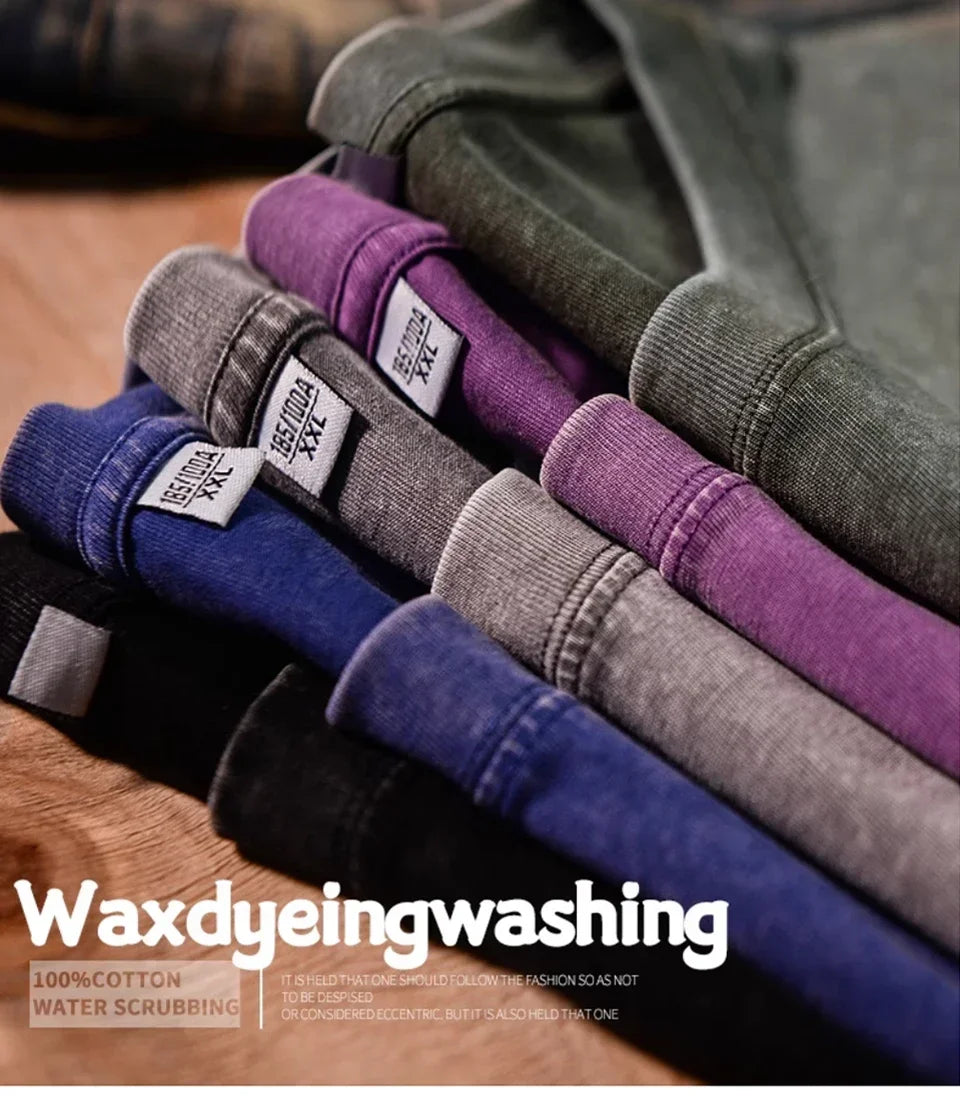 A stack of dark colored t-shirts showing various shades of purple, gray, and blue fabric.