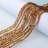 A close-up of a strand of warm amber faceted glass beads used for jewelry making.