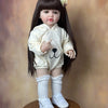 A lifelike 55 cm soft silicone baby doll with long black hair wearing a cream-colored outfit and white socks.