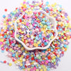 A pile of colorful polymer clay sprinkles mix in various shades of pink, blue, yellow, and green.