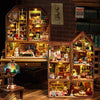 A wooden miniature dollhouse kit featuring detailed furniture and figures displayed in glass cabinets.