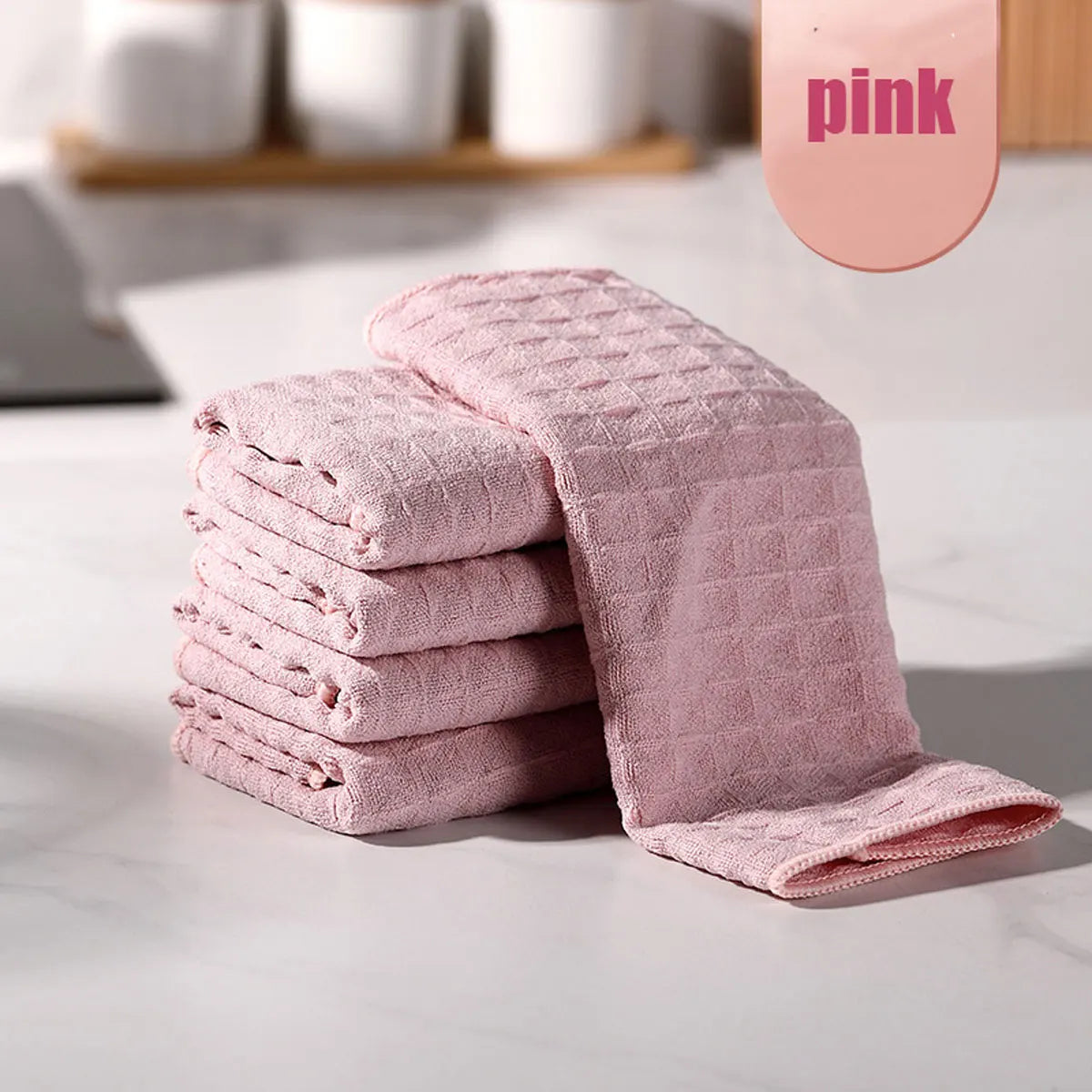 A stack of pink ultra-absorbent microfiber kitchen cleaning cloths is displayed on a white marble surface.