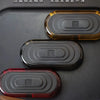 Three different colored EDC push slider fidget toys are displayed on a dark surface.