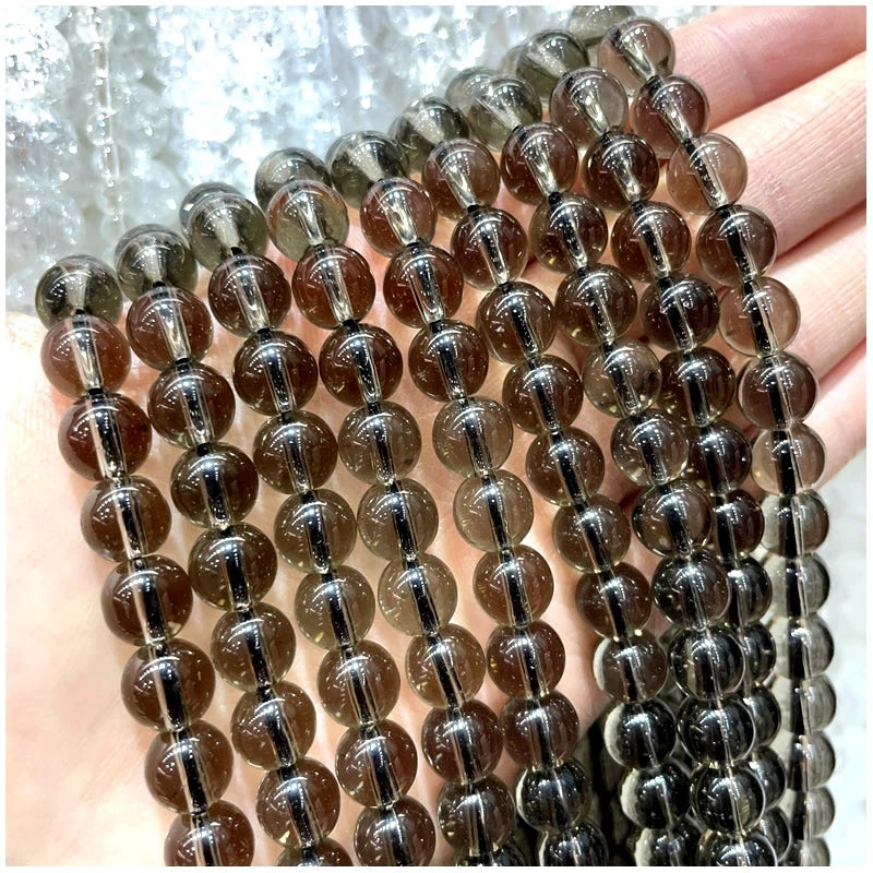 A hand holds a strand of natural stone beads, including amethyst, garnet, and labradorite varieties.