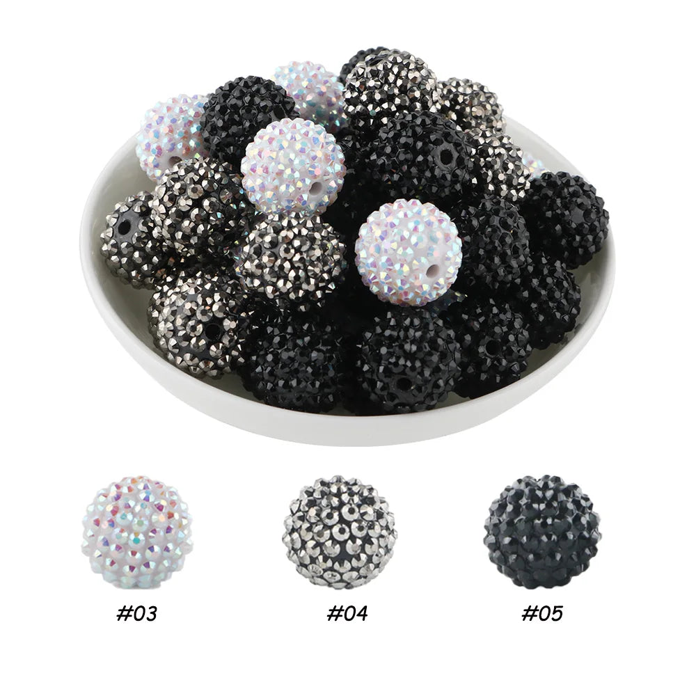 A pile of black and iridescent white rhinestone resin bayberry beads for jewelry making