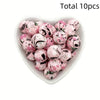 A heart-shaped dish filled with ten pink and black patterned silicone beads for DIY jewelry making