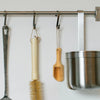 A set of three natural wooden scoop spoons hanging on a metal rack.