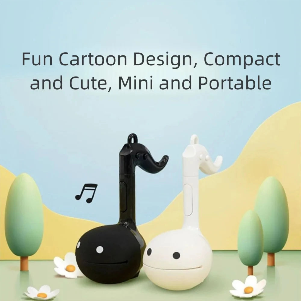 A white and black Otamatone mini electronic musical instrument toy with a musical note symbol on the background.