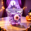 A translucent purple fidget cube shaped like a ghost with festive holiday designs rests on a wooden surface.