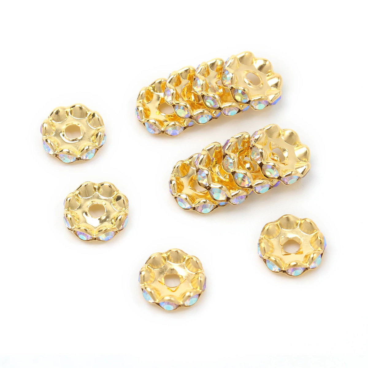 A collection of gold-toned crystal rhinestone spacer beads for jewelry making, arranged in various shapes and sizes.