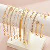 A collection of 11 gold and crystal bracelets featuring heart, infinity, and charm designs displayed on a white surface.