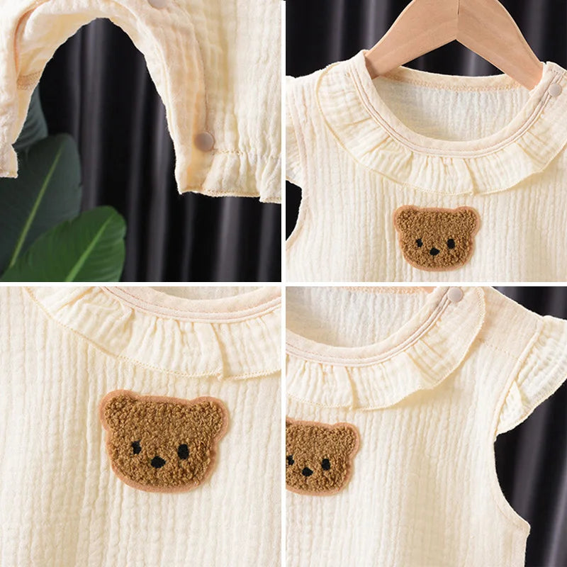 A set of cream-colored cotton muslin baby romper and hat featuring a brown bear applique.