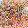 A close-up view of small, round, flatback glass crystal rhinestones in shades of amber and gold.