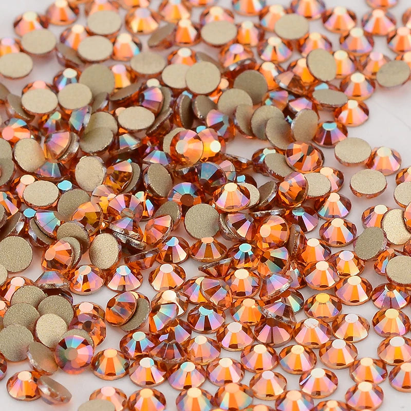 A close-up view of small, round, flatback glass crystal rhinestones in shades of amber and gold.