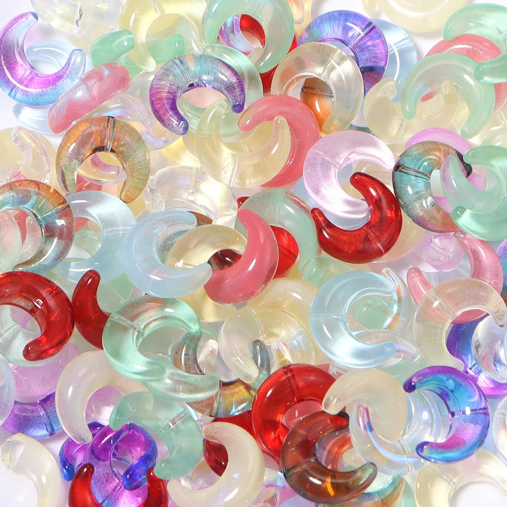 A close-up view of various translucent glass beads shaped like the moon in multiple colors including pink, purple, green, and