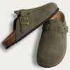 A pair of olive green suede cork mules with brass buckles and arch support.