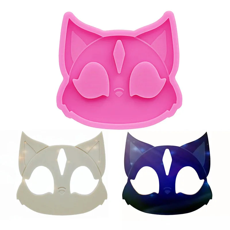 Pink silicone mold of a cat head for DIY keychains and craft projects shown alongside white and blue cat face masks