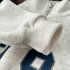 Close-up of a light gray kids sweater cuff and fabric detail on a matching set.