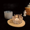 A clear crystal silicone candle mold sits on a woven mat with a lit candle in a dark setting.