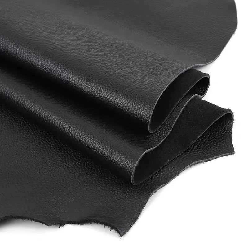 Black cowhide leather fabric folded and draped, showing a smooth texture.