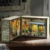 A wooden miniature dollhouse kit featuring a flower shop facade with detailed furniture and lighting elements.