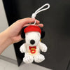 A white Snoopy plush toy wearing a red cap and a yellow sandwich bag charm is being held by a hand.