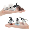 A hand holds a set of realistic mini ocean animal figurines including a whale, shark, dolphin, turtle, and penguin.