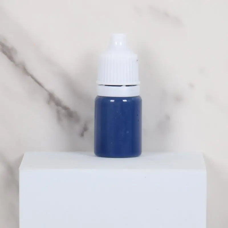 A small blue bottle with a white cap sits on a white surface.
