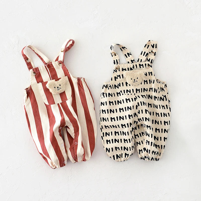 A pair of striped baby rompers in beige and terracotta with small bear decorations.
