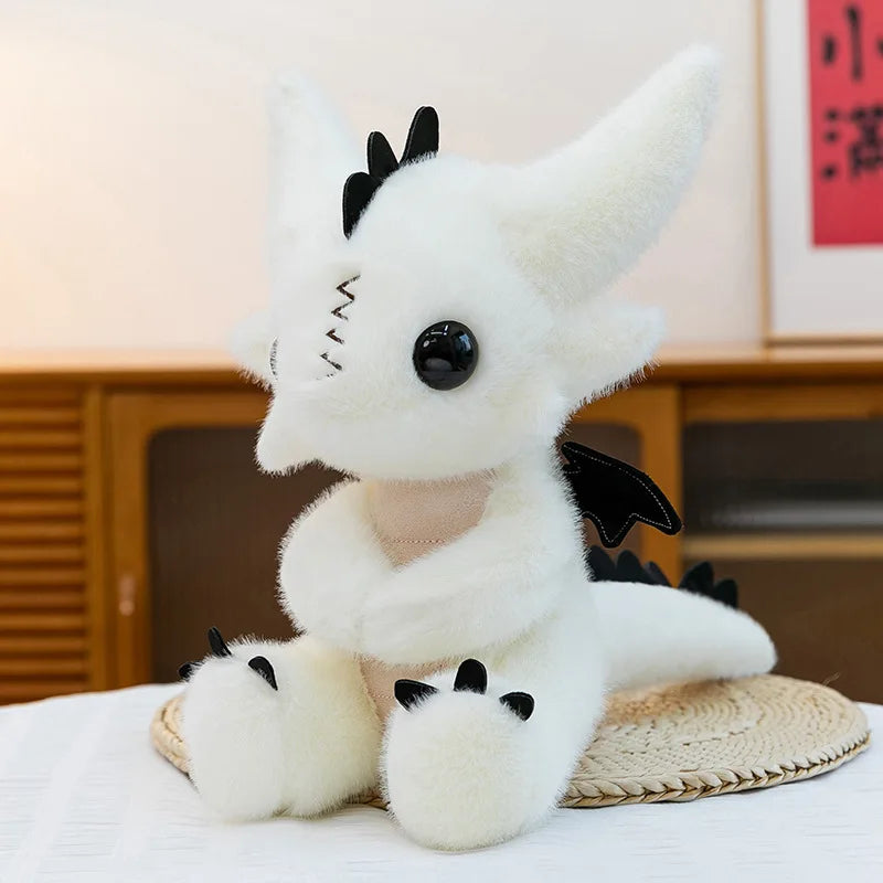 A white Toothless dragon plush toy with black horns and wings sitting on a light-colored surface.