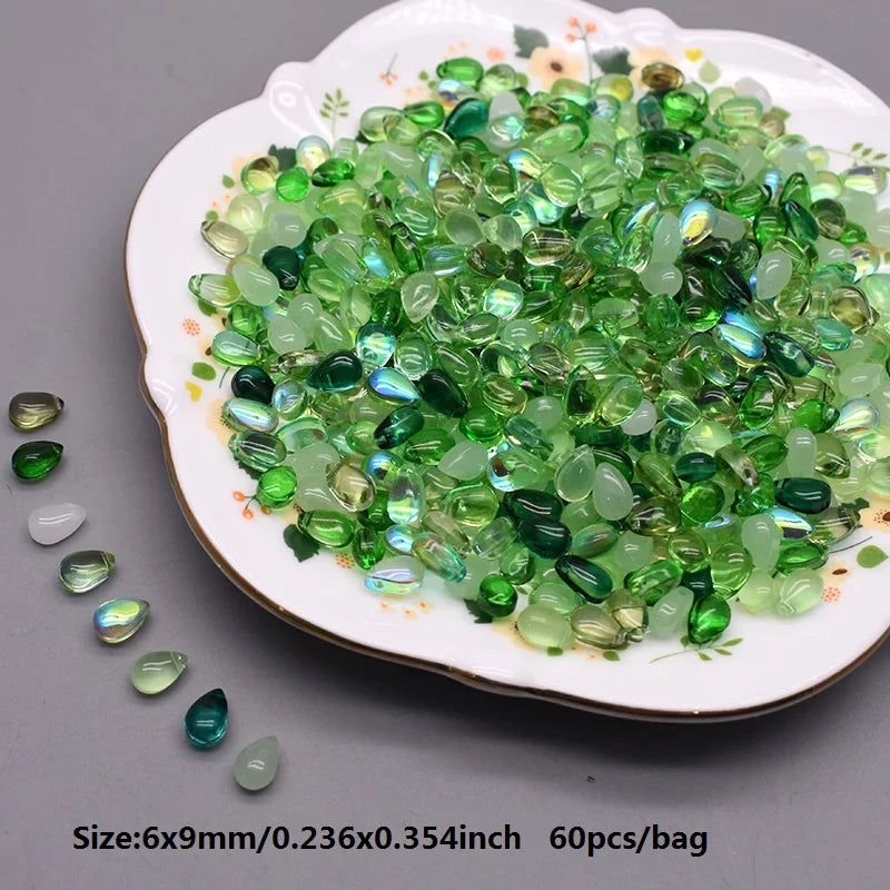 A pile of green and clear water drop Czech glass beads for jewelry making