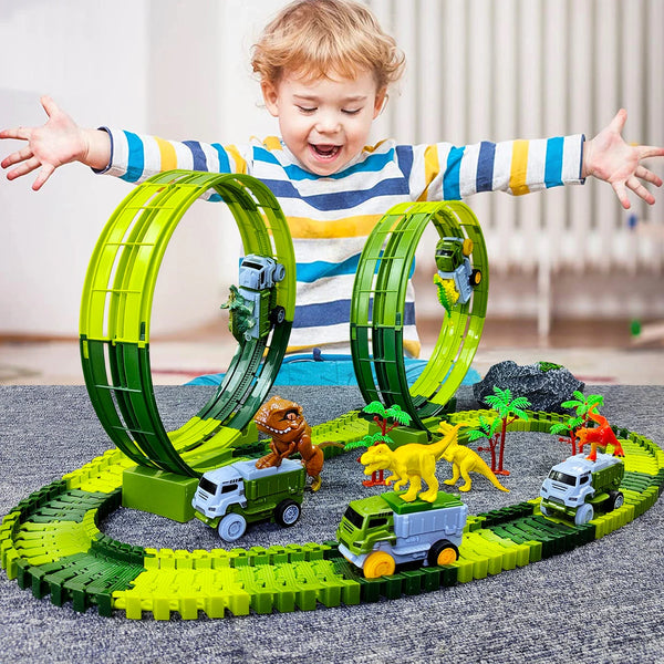 A child is holding a green dinosaur race track model with various vehicles and dinosaurs on a gray surface.
