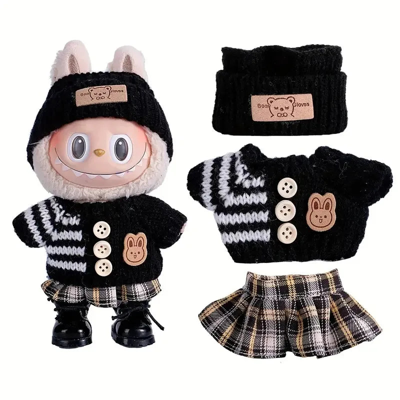 A set of black and white knitted clothing for a doll figure including a hat, gloves, and shorts.
