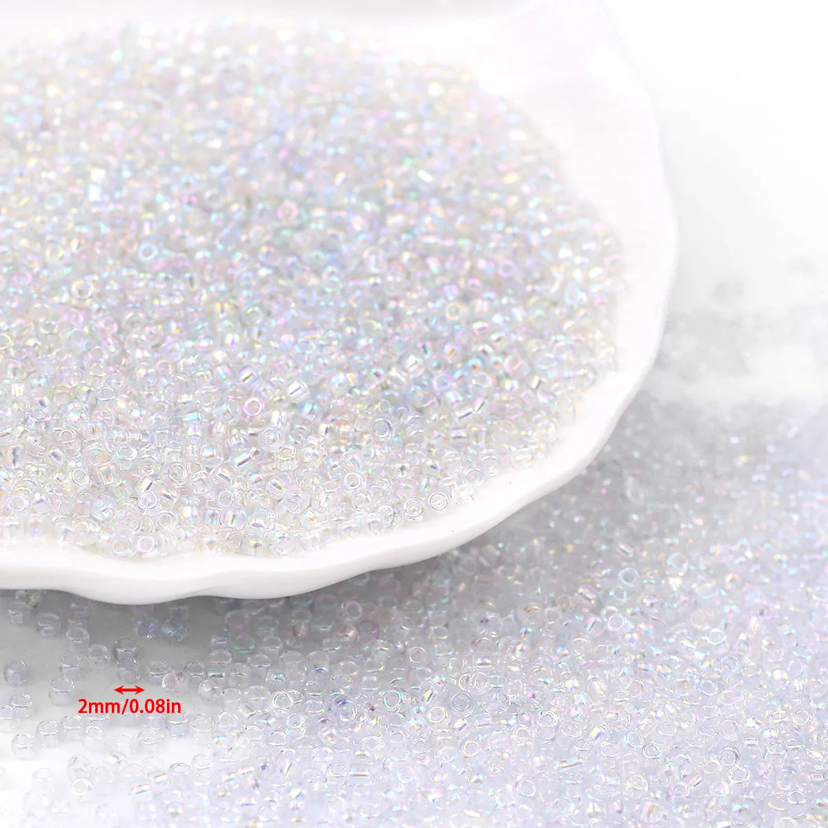 A close-up view of clear, iridescent glass seed beads scattered on a white dish.