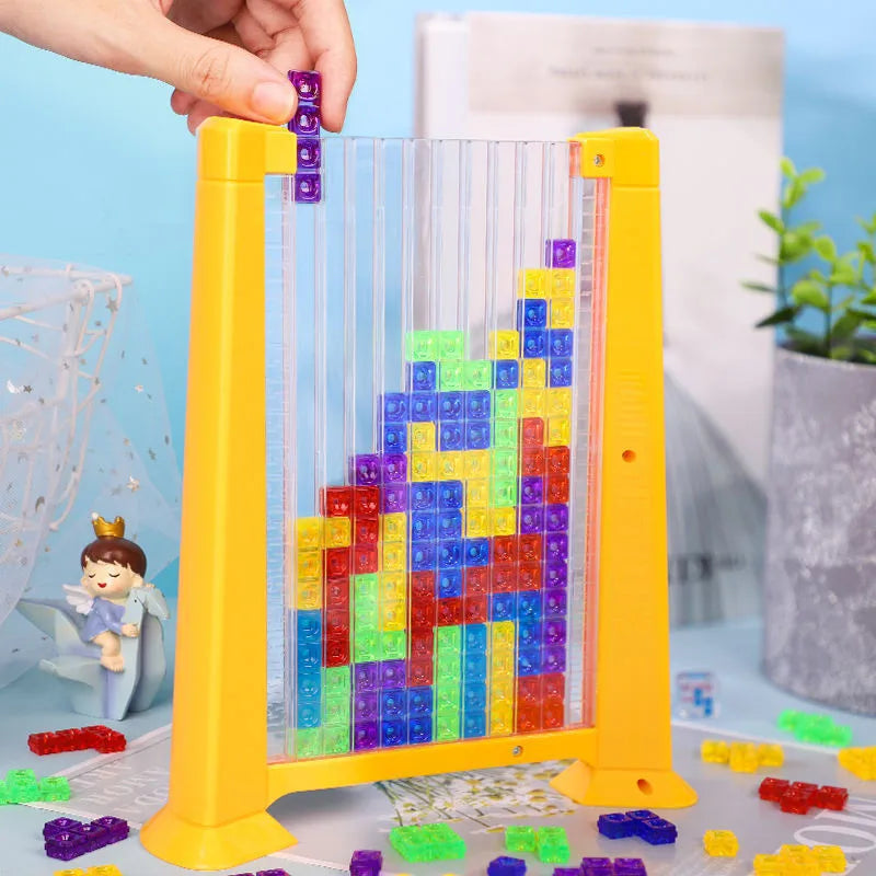A yellow plastic puzzle frame filled with colorful translucent building blocks and a hand inserting a purple block.