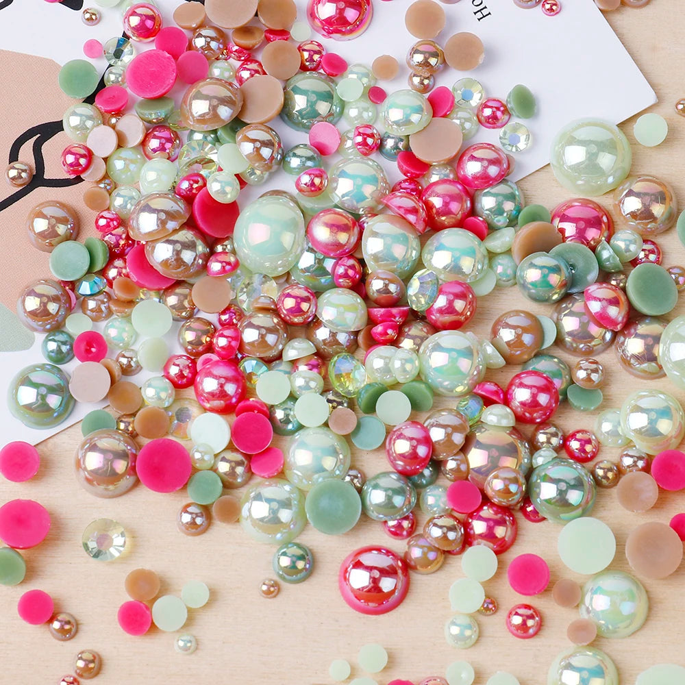 A colorful mix of resin and rhinestone pearls in pink, green, and gold tones scattered on a wooden surface.