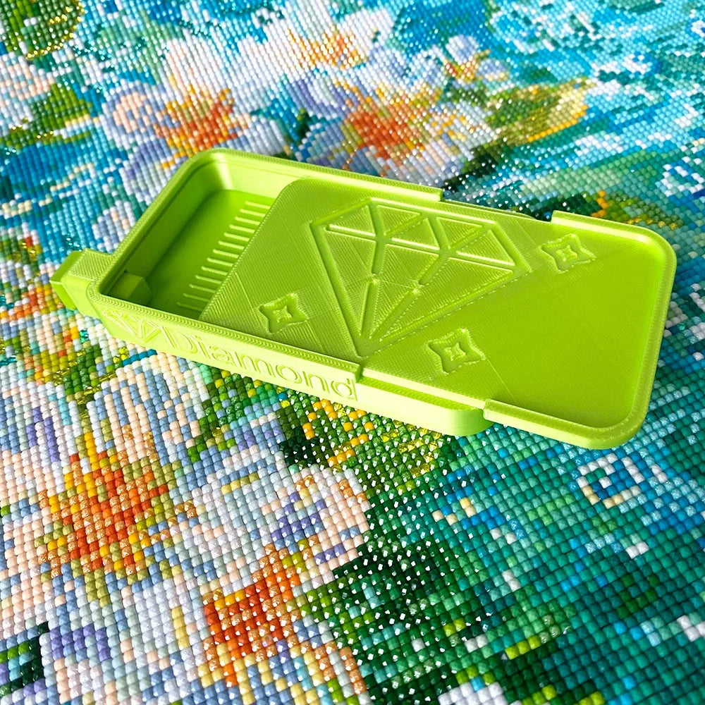 A lime green diamond painting organizer tray with storage compartments placed on a colorful fabric background.