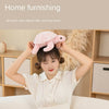 A young woman is holding a pink sea turtle plush toy above her head in a brightly lit room.