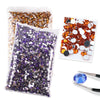 A collection of flat-back resin rhinestones in various colors including gold, purple, and silver, displayed in a clear plasti
