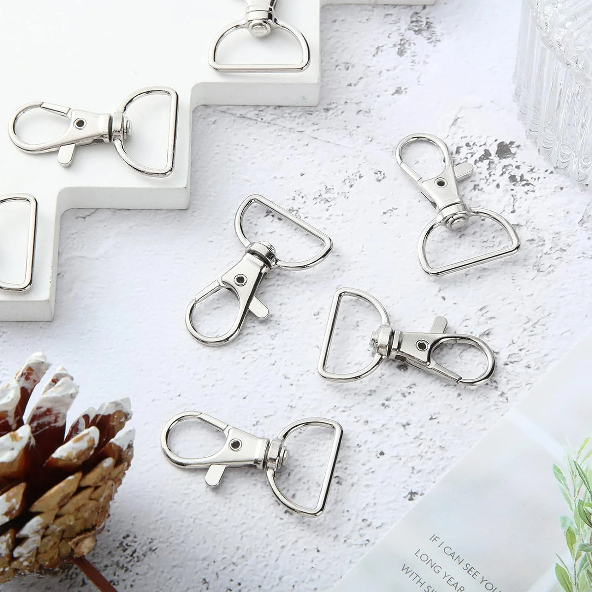A collection of silver swivel snap hooks with D-rings displayed on a white surface.