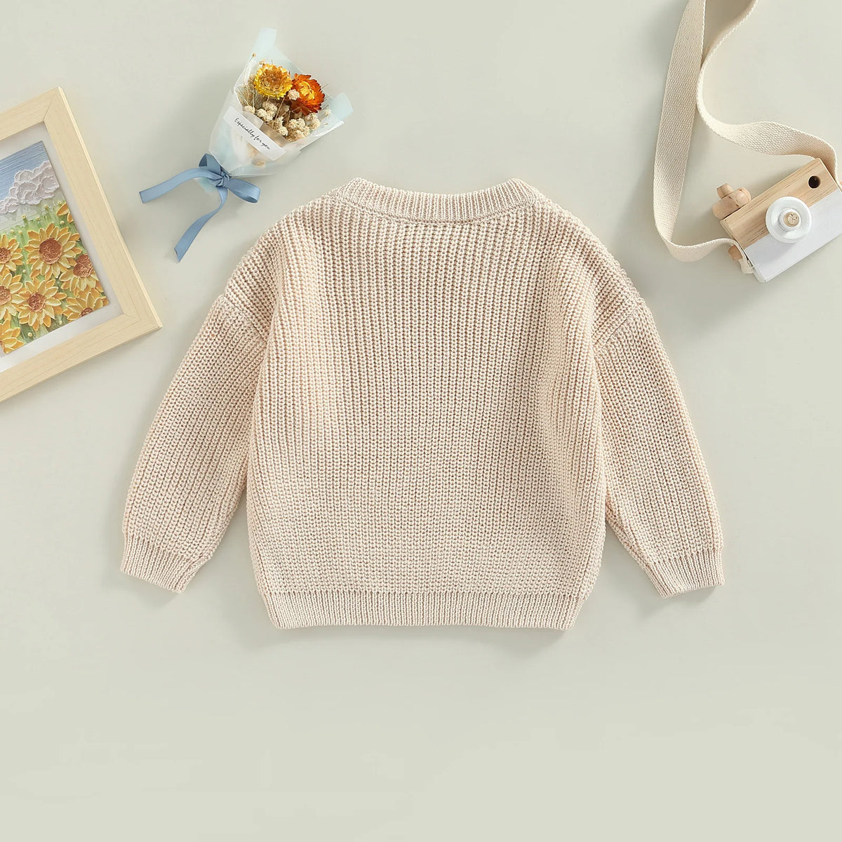 A beige knit pullover sweater for kids with long sleeves, displayed on a light background.